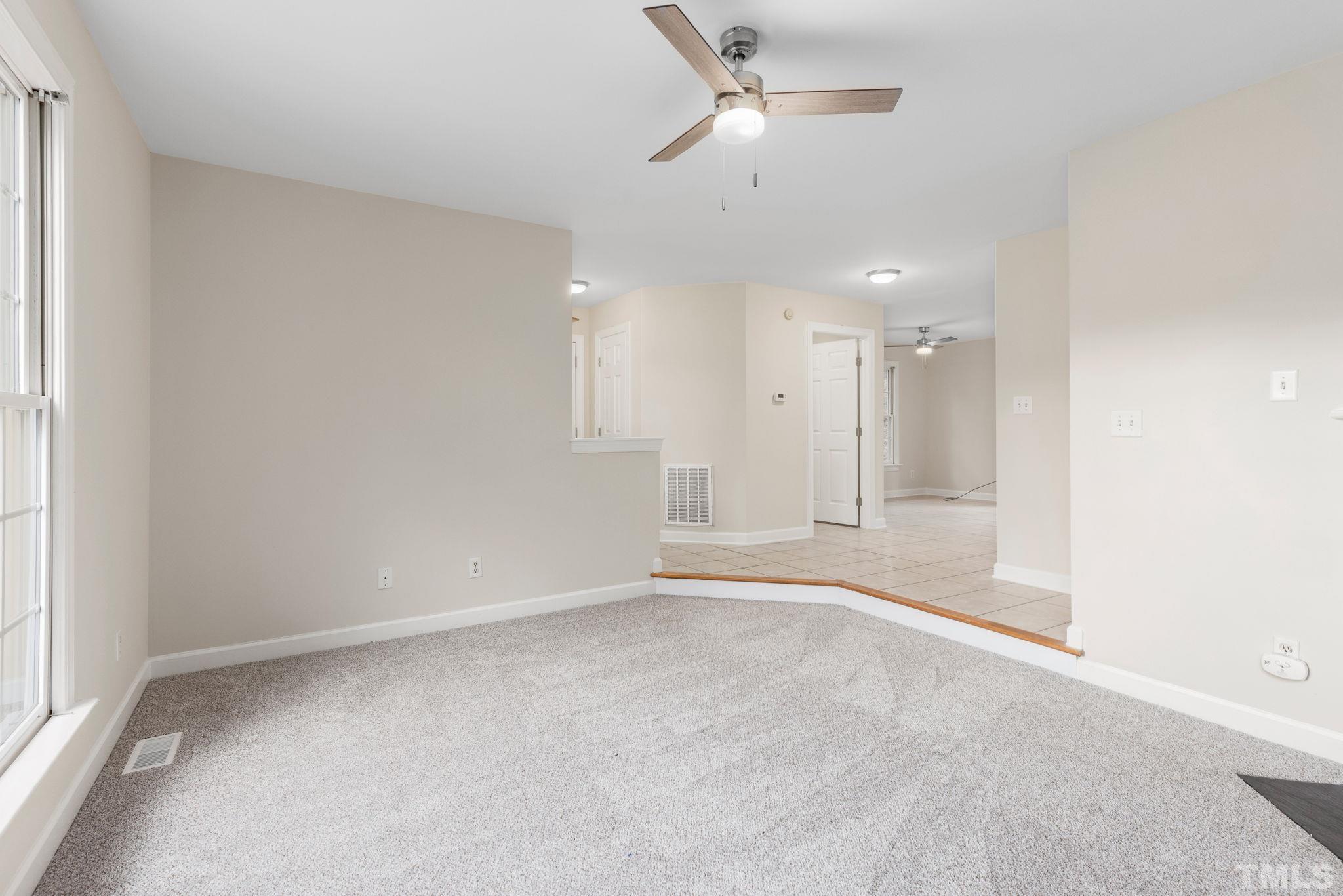 4313 Timberwood Drive Raleigh, NC 27612 - Photo 7 of 28 an empty room with a ceiling fan and a window