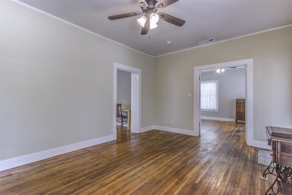 2220 West Rosedale Street South Fort Worth, TX 76110 - Photo 9 of 33 a view of an empty room with wooden floor and a ceiling fan