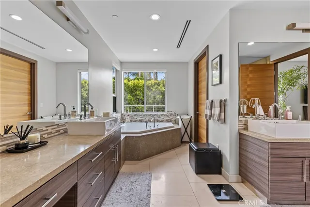 a bathroom with double vanity sinks a large mirror and a bath tub