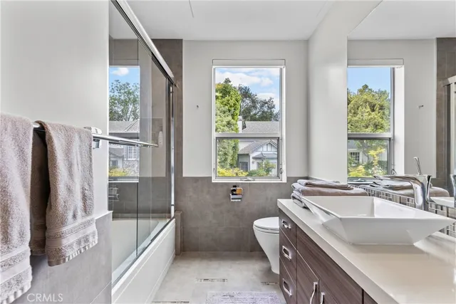 a bathroom with a granite countertop sink a toilet a mirror and shower