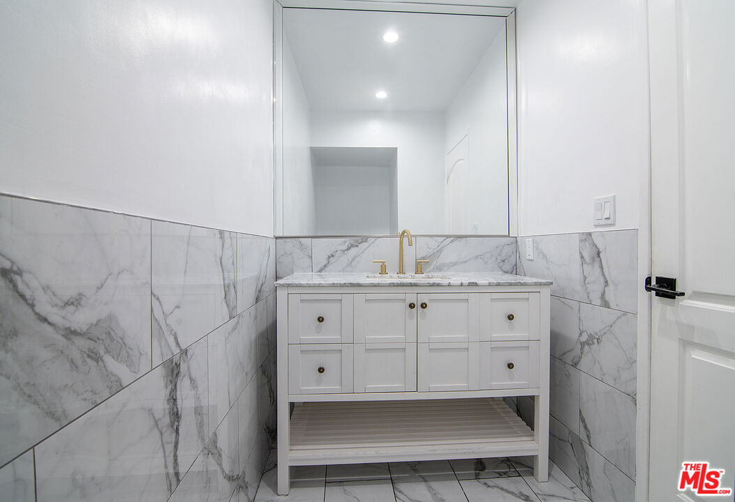 853 Le Doux Road, Unit 201 Los Angeles, CA 90035 - Photo 20 of 36 a bathroom with a granite countertop sink a mirror and shower