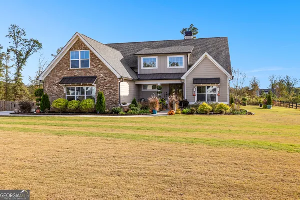 a view of a big house with a big yard and large trees