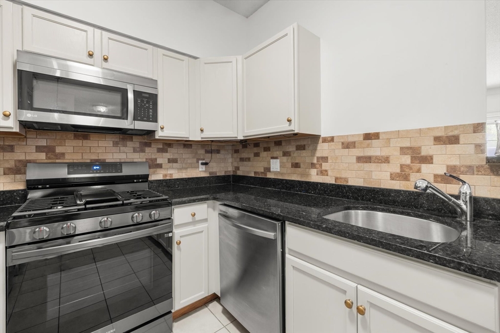 21 Hampshire Road, Unit 101 Methuen, MA 01844 - Photo 8 of 18 a kitchen with granite countertop a sink stove and microwave
