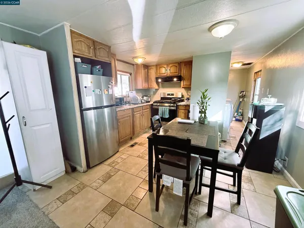 a kitchen with stainless steel appliances a refrigerator a stove a sink dishwasher and a dining table with wooden floor