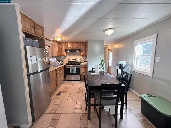 a kitchen with stainless steel appliances kitchen island granite countertop a table chairs and a refrigerator