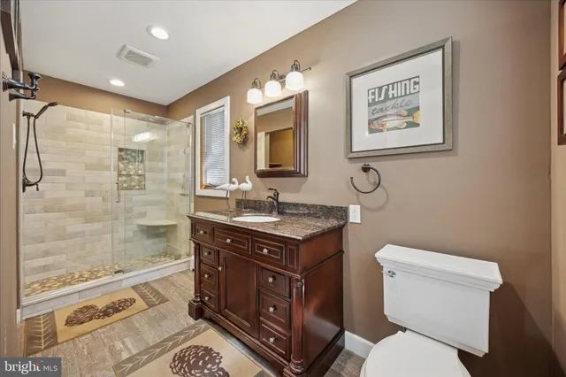 a bathroom with a granite countertop toilet sink and mirror