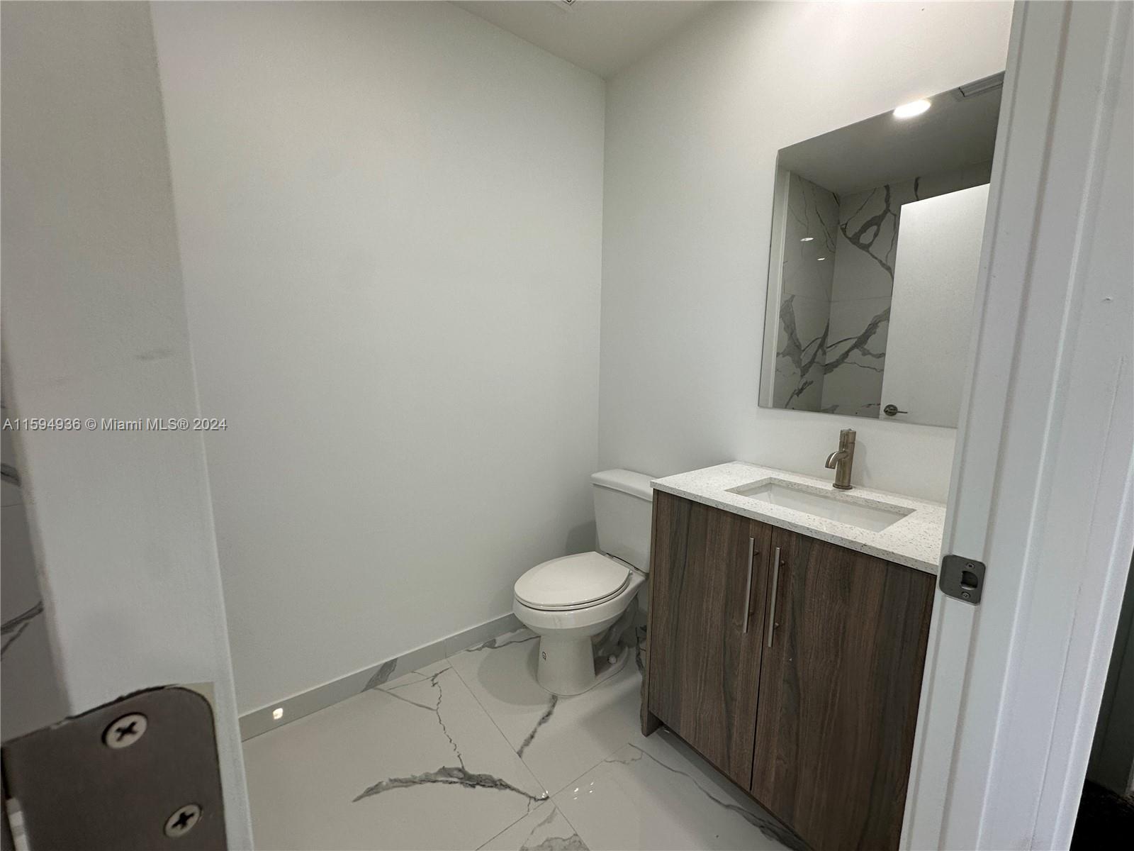 232 Northwest 13th Street, Unit 232 Homestead, FL 33030 - Photo 12 of 14 a bathroom with a toilet sink and mirror