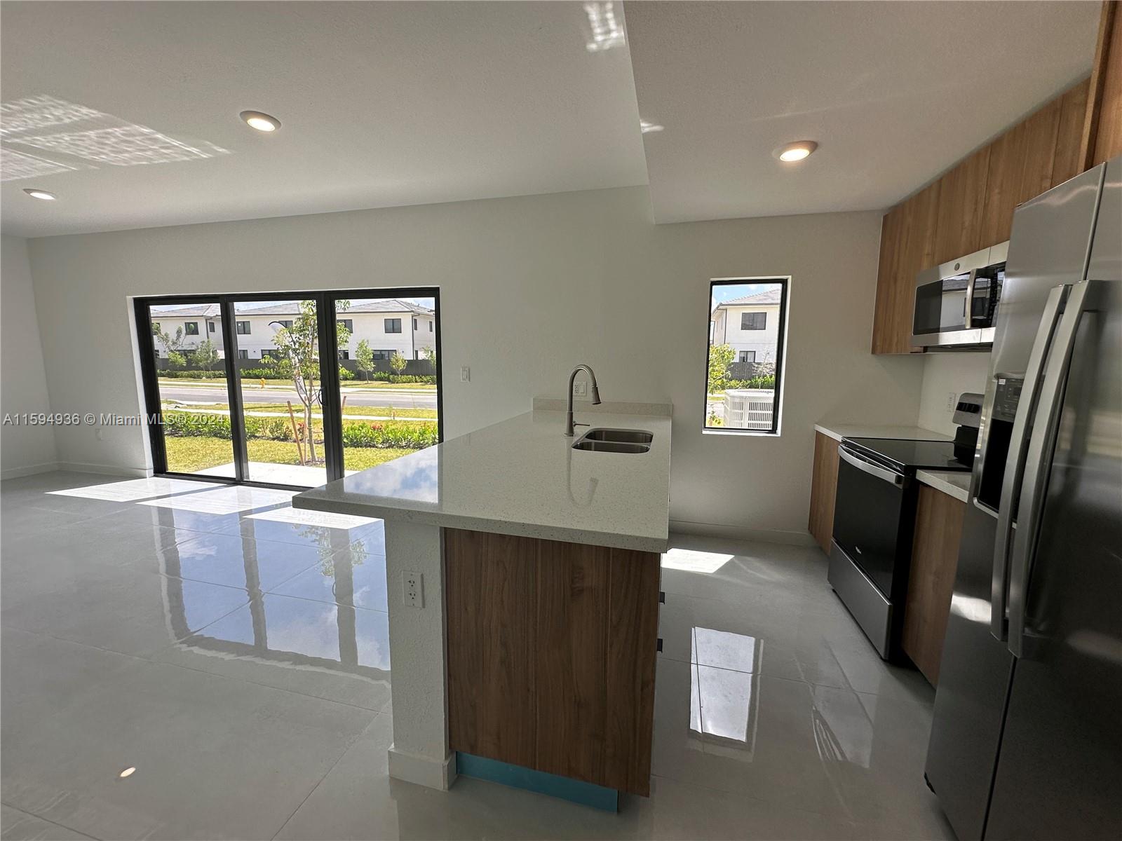 232 Northwest 13th Street, Unit 232 Homestead, FL 33030 - Photo 13 of 14 a kitchen with stainless steel appliances a refrigerator sink and wooden cabinets
