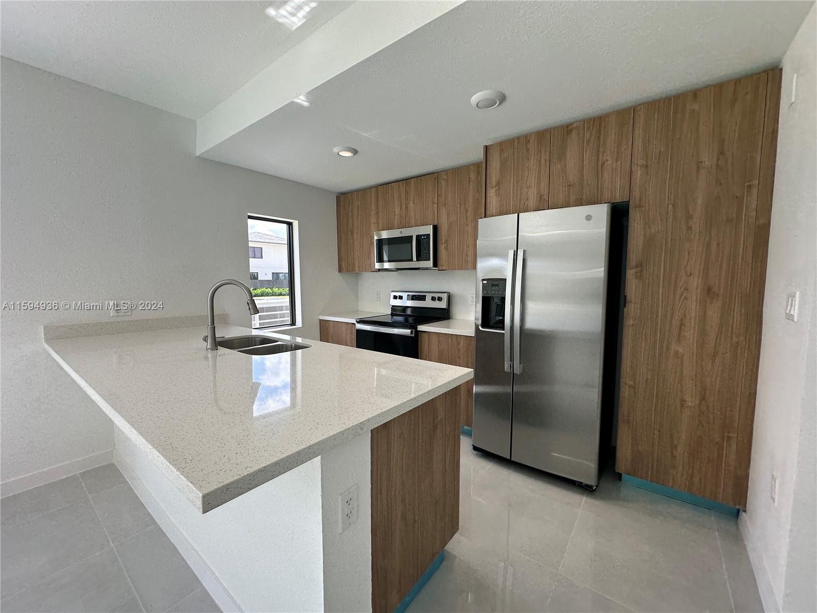 232 Northwest 13th Street, Unit 232 Homestead, FL 33030 - Photo 6 of 14 a kitchen with kitchen island a counter top space cabinets and stainless steel appliances