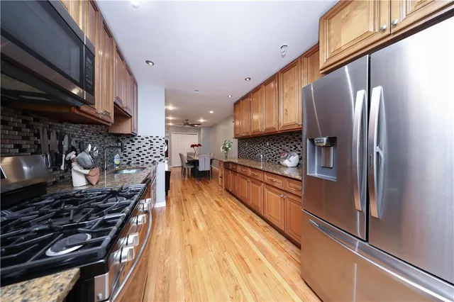a kitchen with stainless steel appliances granite countertop a refrigerator a stove and a wooden floors