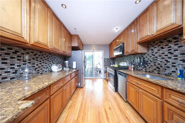 a kitchen with granite countertop a sink a counter top space stainless steel appliances and cabinets