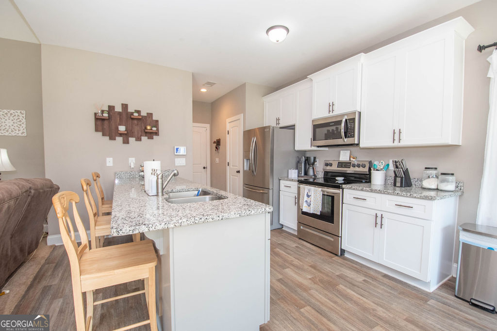 2046 Mcwilliams Barber Road Luthersville, GA 30251 - Photo 27 of 43 a kitchen with stainless steel appliances kitchen island granite countertop a sink dishwasher a stove a refrigerator with a dining table and chairs