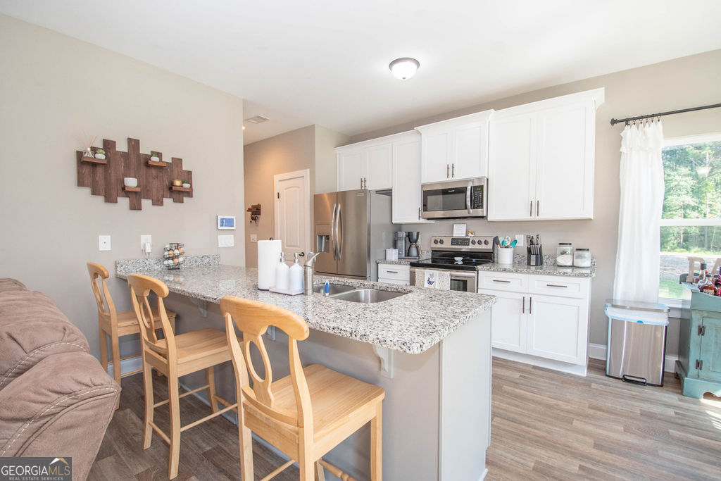 2046 Mcwilliams Barber Road Luthersville, GA 30251 - Photo 28 of 43 a kitchen with stainless steel appliances granite countertop a stove top oven a sink dishwasher a dining table and chairs with wooden floor