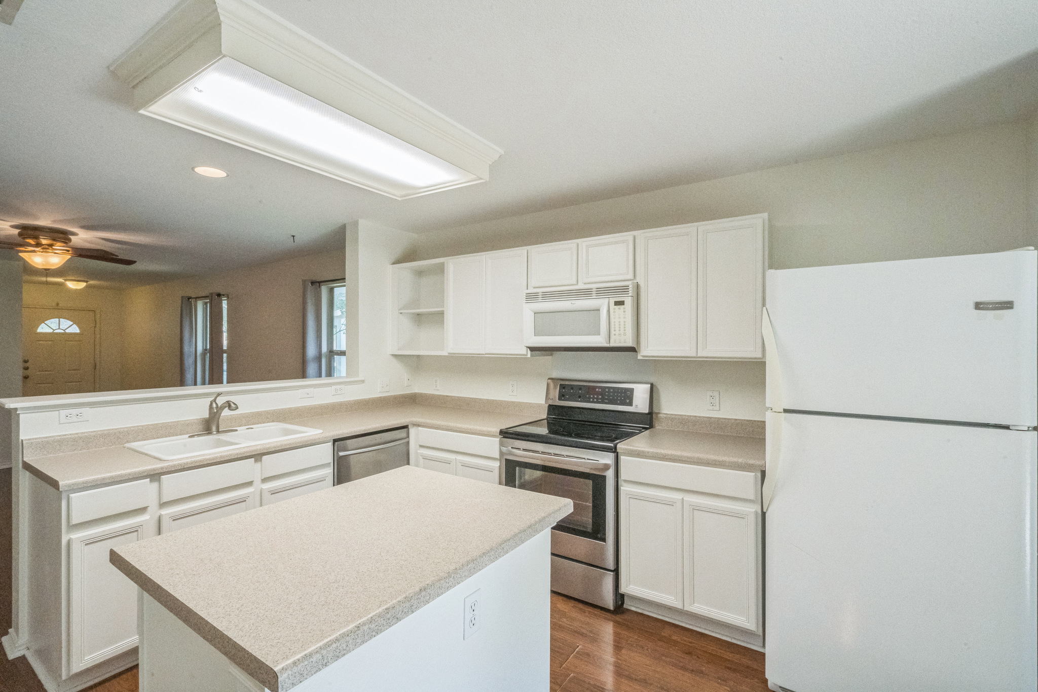 77 Jan Lane Georgetown, TX 78626 - Photo 7 of 16 A well-lit kitchen with a central island and white cabinetry offers a functional and welcoming space.