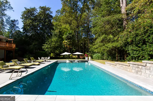 a view of a swimming pool with lawn chairs under an umbrella
