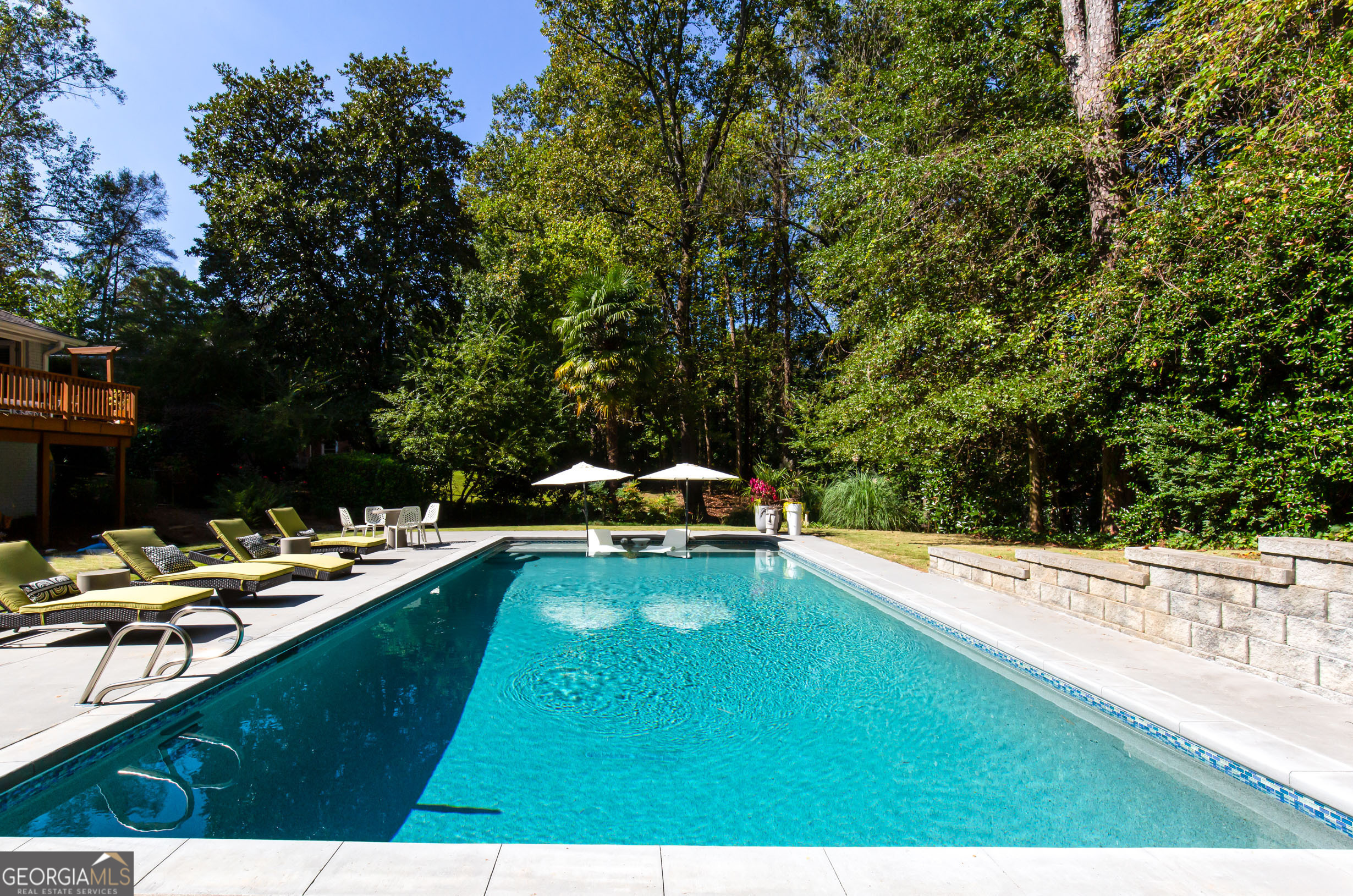 a view of a swimming pool with lawn chairs under an umbrella