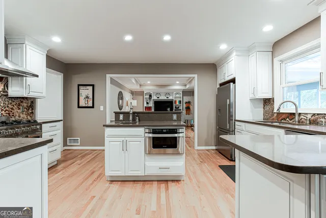 a kitchen with stainless steel appliances kitchen island granite countertop a stove and a sink
