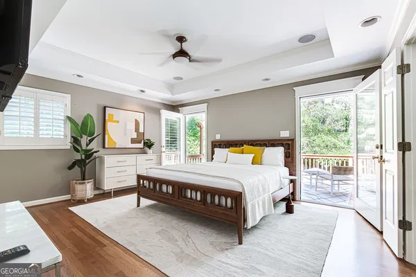 a spacious bedroom with a large bed a chandelier and windows
