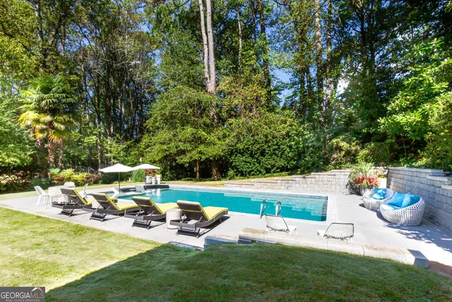 a view of a patio with lawn chairs plants and large trees