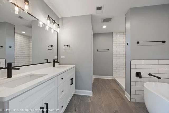a bathroom with a double vanity sink a mirror and a bathtub