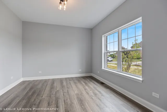 a view of empty room with wooden floor and ceiling fan