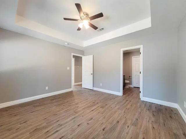 an empty room with wooden floor and ceiling fan