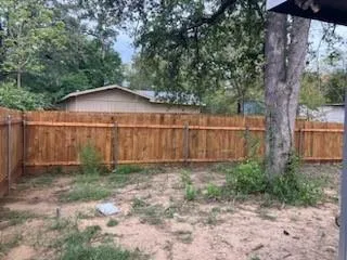 a view of a small yard with a large tree and wooden fence