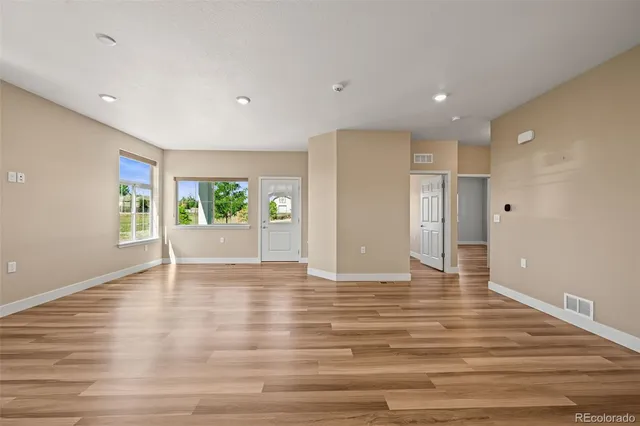 a view of an empty room with wooden floor and a window