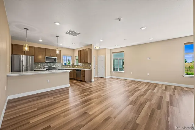 a large kitchen with stainless steel appliances kitchen island a large counter top and wooden floors