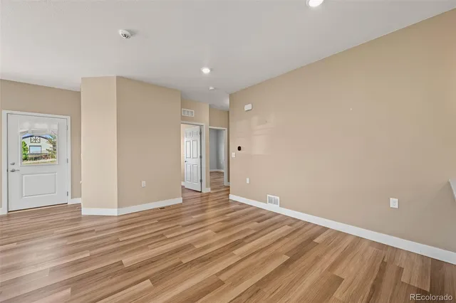 a view of an empty room with wooden floor and closet