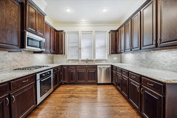 a kitchen with stainless steel appliances granite countertop wooden cabinets a stove top oven a sink and dishwasher