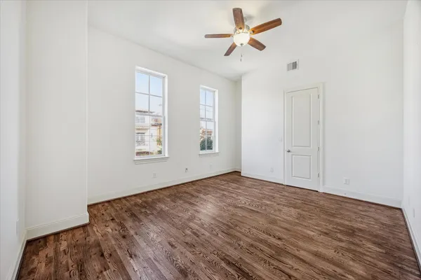 a view of empty room with wooden floor and fan
