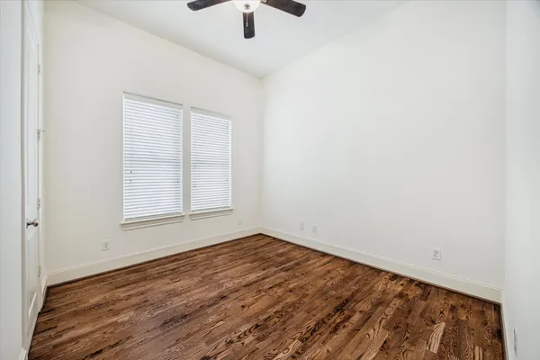 an empty room with wooden floor cabinet and windows