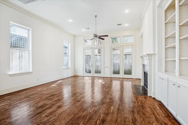 a view of an empty room with wooden floor and windows