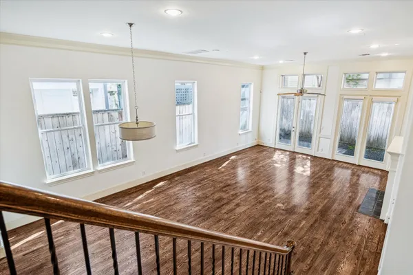 a view of an empty room and kitchen with wooden floor