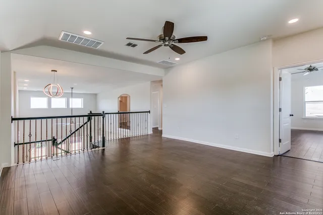 a view of a hallway with wooden floor and a ceiling fan