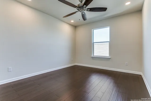 an empty room with wooden floor fan and windows