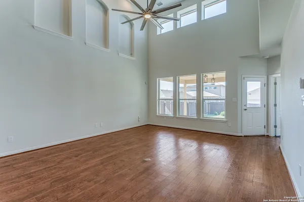 a view of an empty room with wooden floor and a window