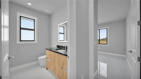 a bathroom with a granite countertop sink a toilet and a mirror
