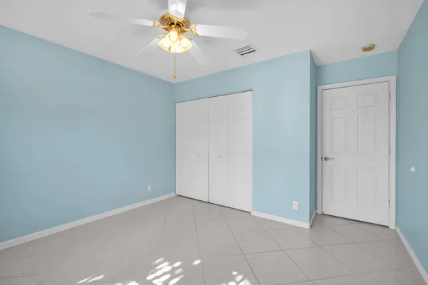 an empty room with a chandelier fan and closet area