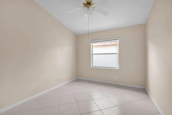 an empty room with a chandelier fan and windows