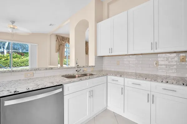 a kitchen with white cabinets and sink