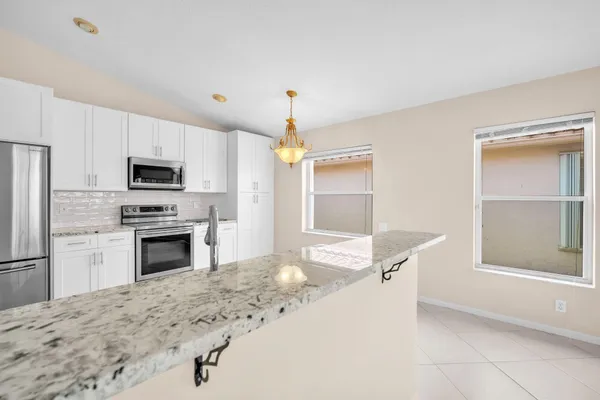 a kitchen with granite countertop a refrigerator and a stove top oven