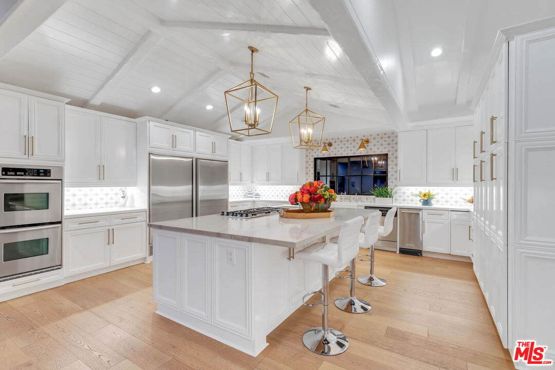 5488 Round Meadow Road Hidden Hills, CA 91302 - Photo 10 of 35 a kitchen with white cabinets and stainless steel appliances