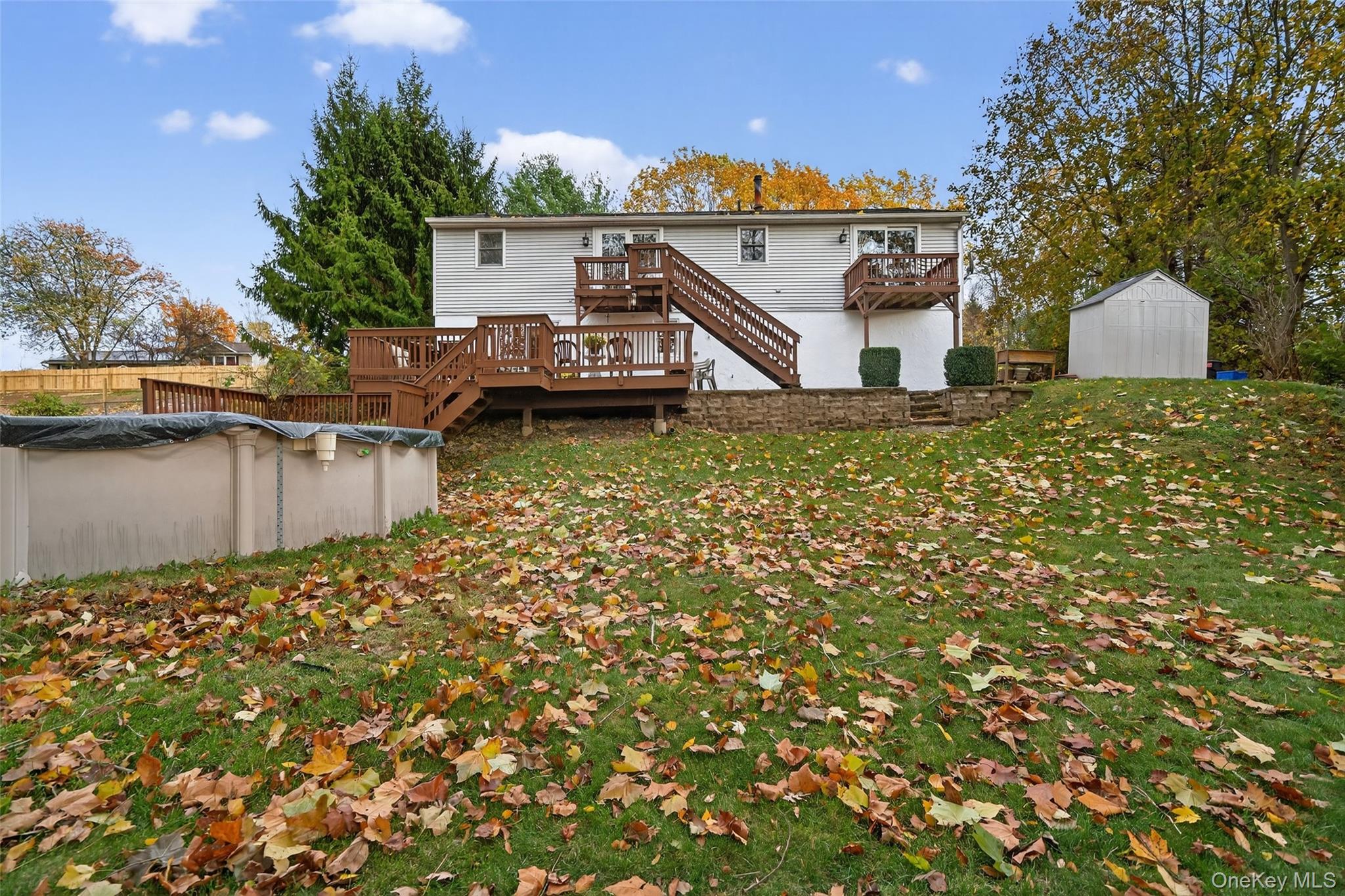 7 Colleen Lane Wallkill, NY 12589 - Photo 37 of 39 Back of property featuring stairs, a deck, a covered pool, a storage unit, and a lawn