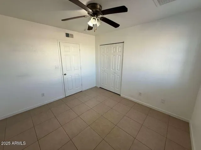 an empty room with a ceiling fan and carpet