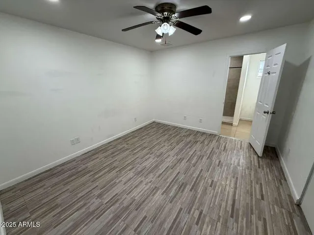 an empty room with wooden floor and a ceiling fan