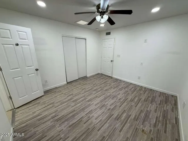an empty room with wooden floor a ceiling fan and staircase