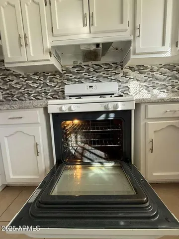 a kitchen with a stove and white cabinets