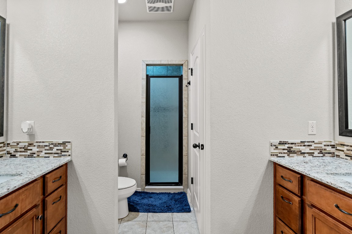 144 Indian Ridge Road Belton, TX 76513 - Photo 12 of 24 Bathroom with backsplash, vanity, a textured wall, light tile patterned floors, and a stall shower